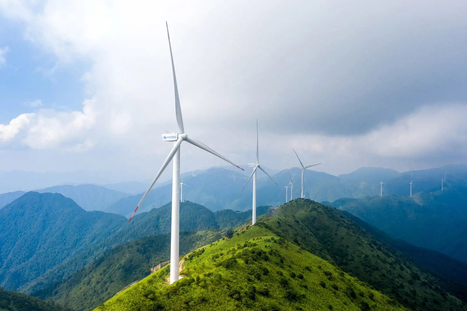 Wind turbines along green peaks