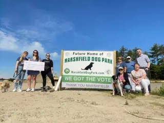 Volunteers at Marshfield Dog Park, and their pets, pose at the site of the new park in Massachusetts, US