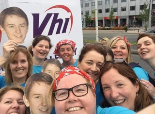 A group of people in blue tshirts and holding photos of Ben as they prepare to take part in a run.