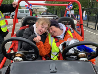 A girl sat in a race car with a volunteer from Speed of Sight after a ride on the track.